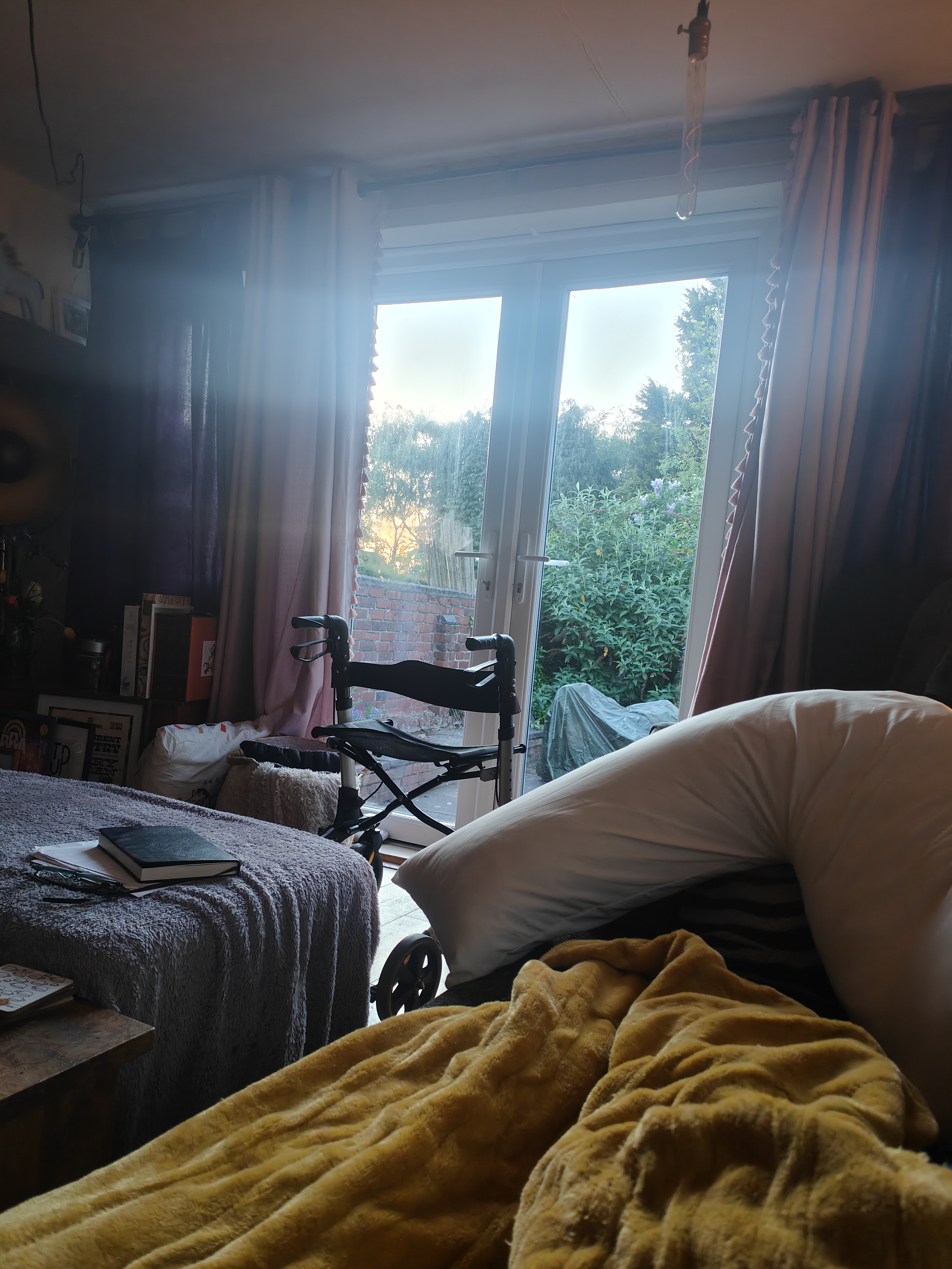 My bedroom on a grey day. My walker parked by the French doors, silhouetted against the garden outside. Cosy blanket pulled up on the bed, notebook sitting untouched on the ottoman. One of those days where the outside world feels very far away. The chair waits patiently by the door, but today we're staying put. FND doesn't care about my plans.